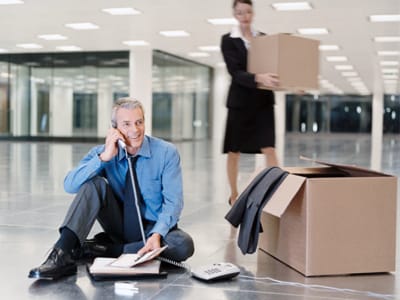 Man in business attire on phone, with moving boxes around him